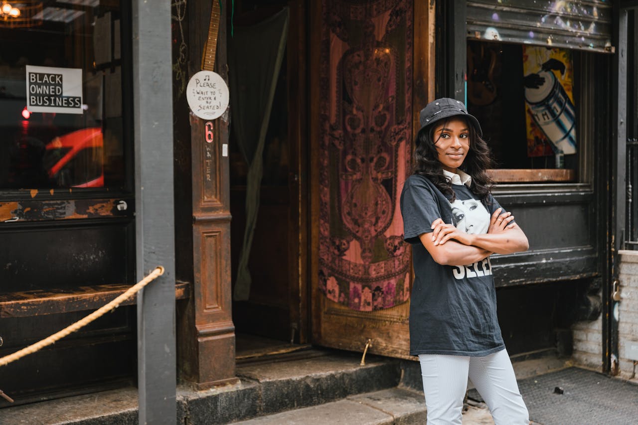Young woman standing confidently outside her black-owned business, embracing pride and community.