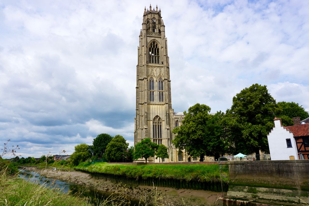 Gothic Boston Stump tower stands majestically in England alongside a scenic river view.